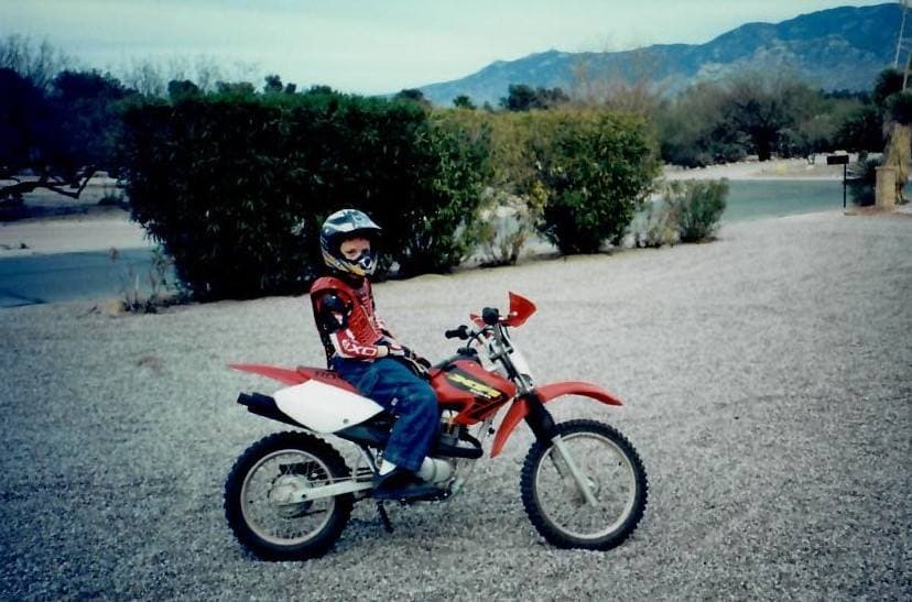 Teenage Alex Bowman sits on a dirt motorcycle wearing a helmet