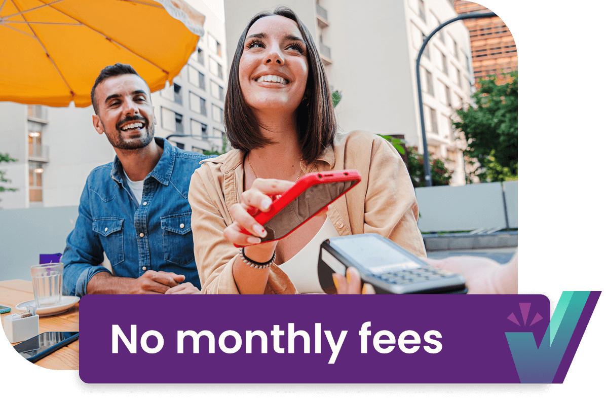 No monthly fees. A young couple smiling as they pay their bill at a restaurant.