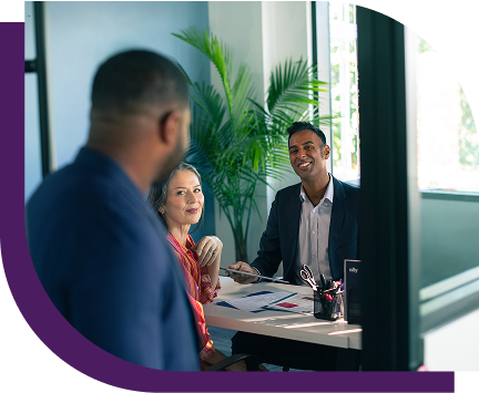 a man peeking into an office to chat with a man and woman.