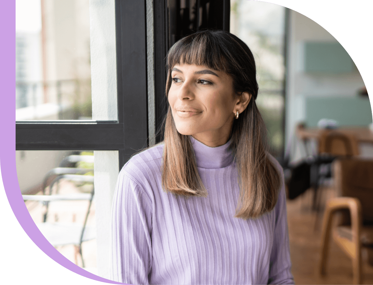 A smiling woman confidently looks out the window.