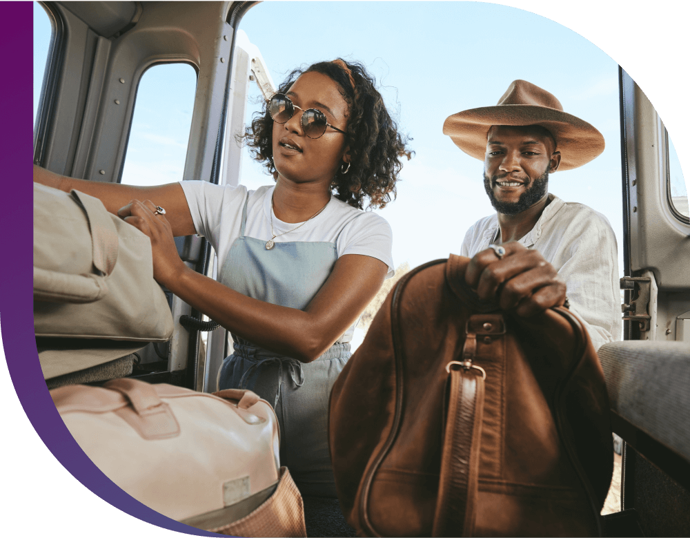 A couple excitedly packs their car with suitcases for a trip.