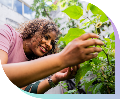 a smiling woman checks on a plant in her garden