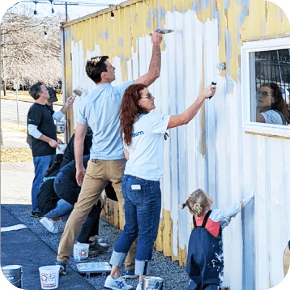 A group of adults and a child painting a building.