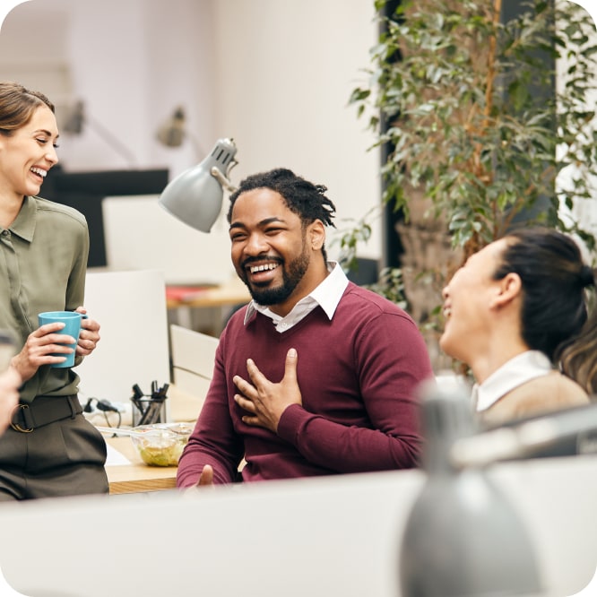Two men and a woman chatting and laughing with each other in an office.