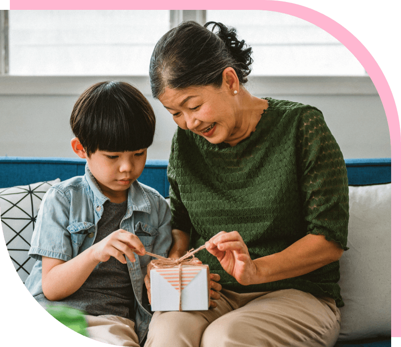 An Asian child and grandparent open a gift together.