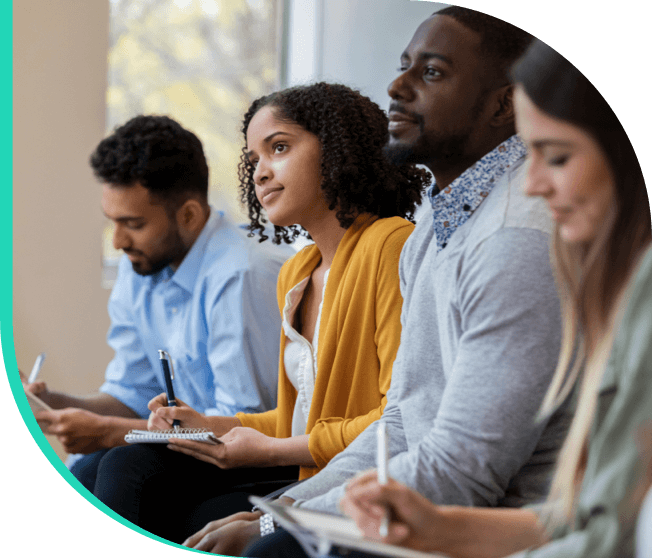 Men and women actively listening while taking notes.