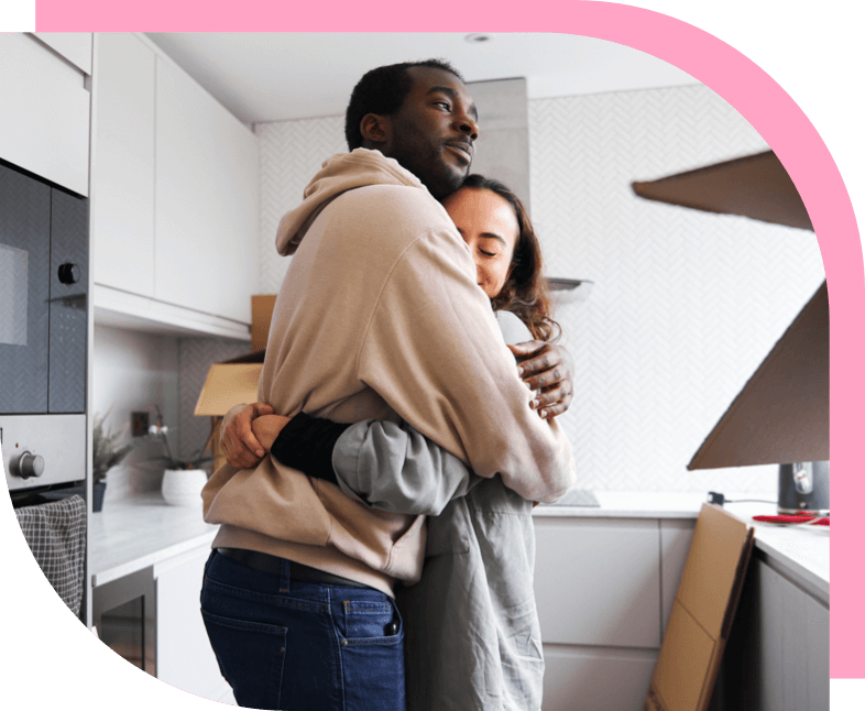A man and woman hugging in their kitchen.