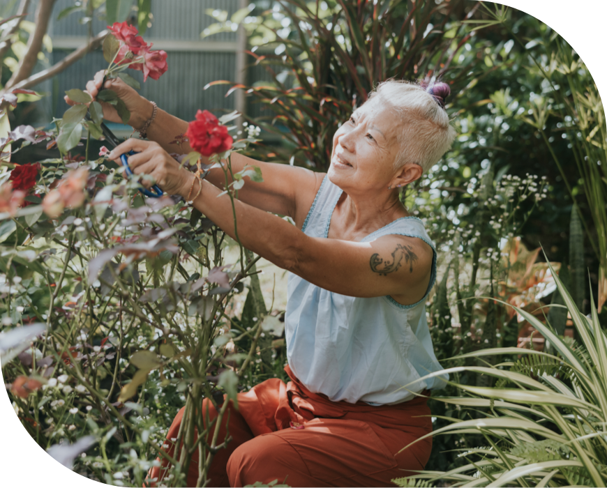 A woman sits in her garden picking flowers
