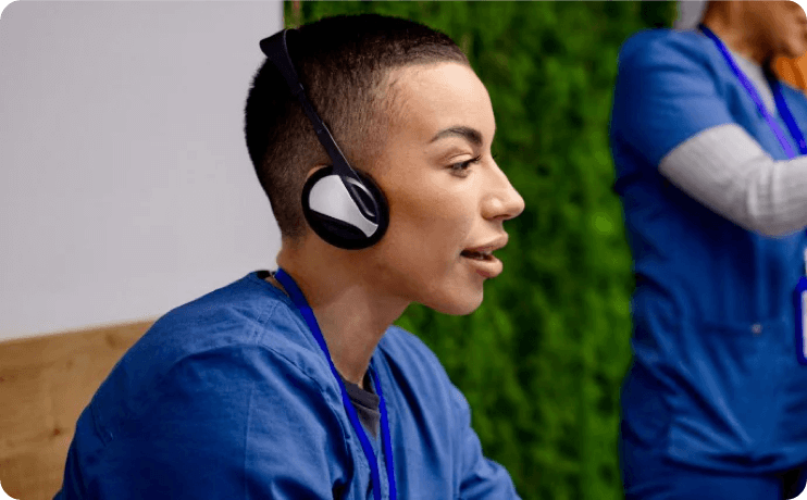 A short-haired person wearing headphones and scrubs.