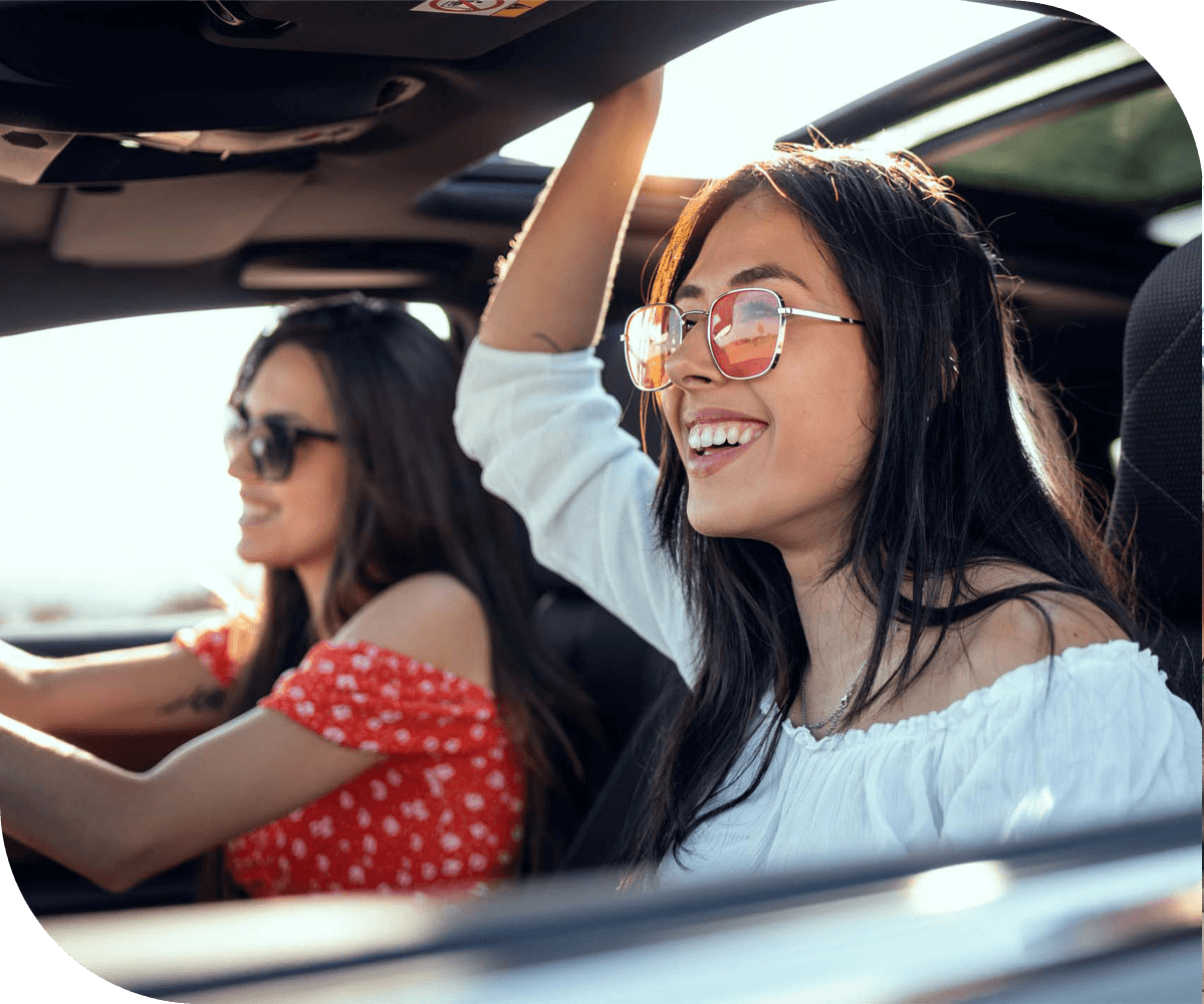 two people wearing sunglasses enjoying a car ride with the windows open on a sunny day