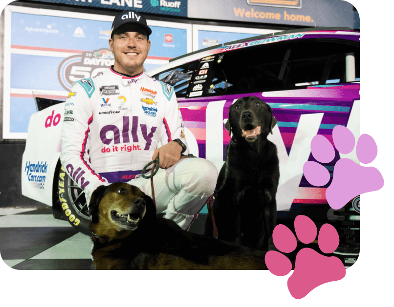 Alex Bowman poses with dogs Roscoe and Finn in front of the Ally car. 