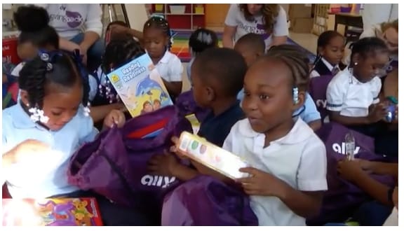 Group of children taking out items from their purple Ally backpacks