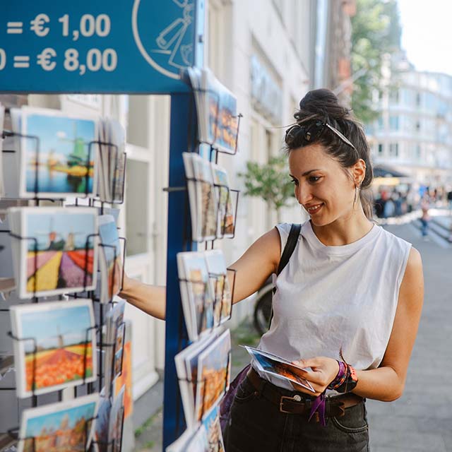 A young woman is looking at postcards during her vacation in Amsterdam. 