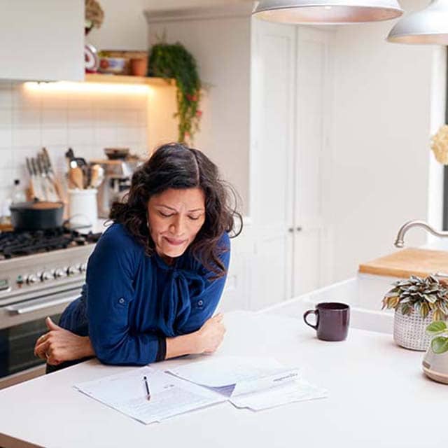 Woman looks over tax documents at the kitchen counter.
