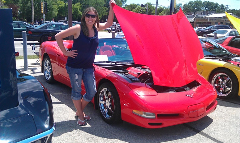 Garozzo poses next to a red Corvette with its hood up