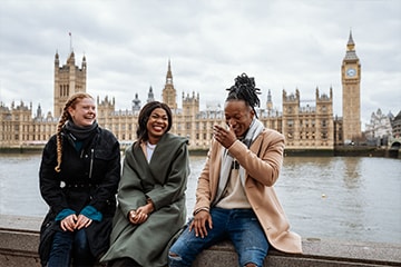 Three friends laughing together on a bridge