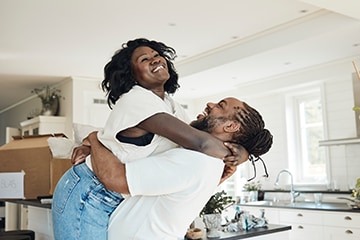  A man lifts a woman into his arms to celebrate moving into their first home together.