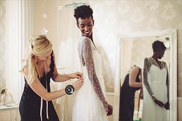 Fashion designer is adjusting the wedding dress on a bride