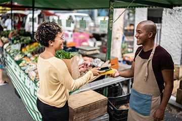 a happy customer tapping their Ally credit card on a payment device