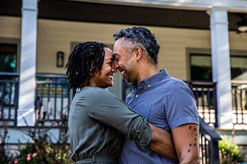 Husband and wife embracing in front of home
