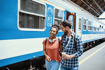  Young woman and man walking by a train while traveling