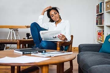 Woman sits in an armchair and reads a newspaper