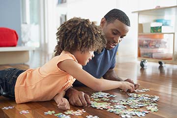 Father and daughter put together a puzzle on the floor