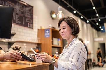 a happy customer tapping their Ally credit card on a payment device