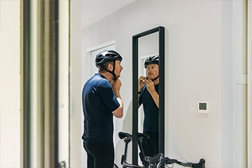  Man puts on a bike helmet in front of a mirror