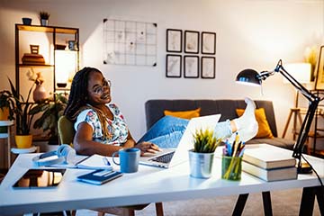 Woman relaxing at home happily checking her online bank account in her home office