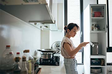 Woman stands at the kitchen counter going over a bill