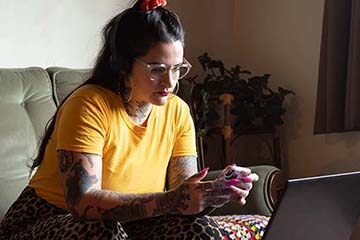 Woman sitting on couch looking at her phone and laptop