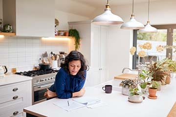 Woman looks over tax documents at the kitchen counter