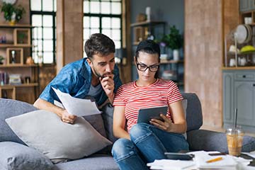 Couple at home on the couch calculating bills.