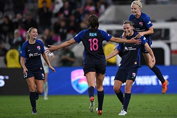  Four female soccer players run on the field in celebration
