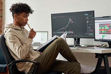Young investor reads about investing while following a stock graph on the computer