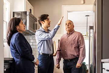  A couple tours a home's kitchen with a real estate agent.