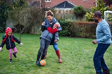 Family of four plays soccer in the backyard