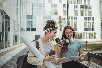 Two women going over papers while walking outside