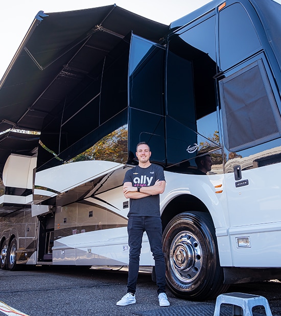 Alex Bowman stands outside of his Prevost tour bus