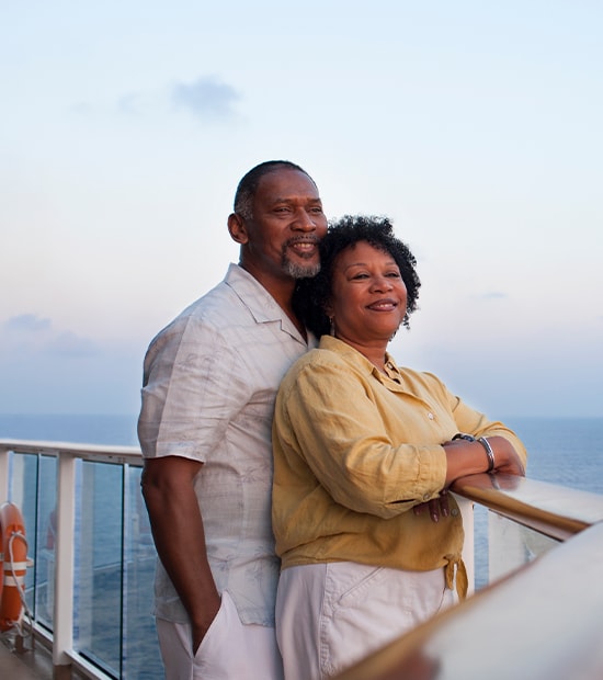  Couple enjoying the sunset while leaning on the railing of their cruise ship.