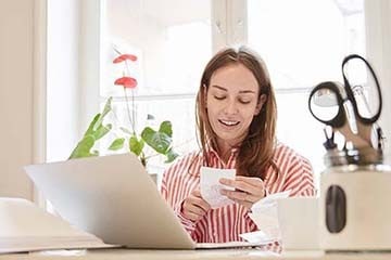 Woman looking at a receipt while sitting at a desk