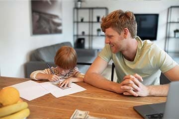 Father teaching his son about money at kitchen table. 