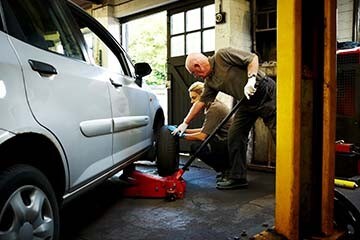 Man and woman replace a tire in a professional garage