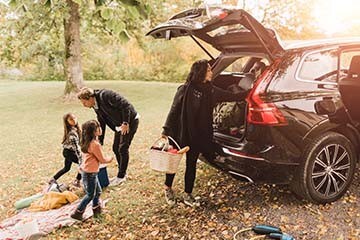 Two children and two adults set up a picnic by an SUV