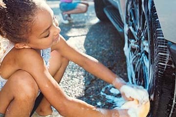 Two children washing a car.