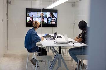 Two business people in a conference room having a virtual meeting with other teammates.