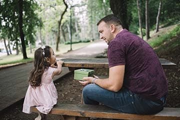 Dad and daughter have a conversation at a picnic table.