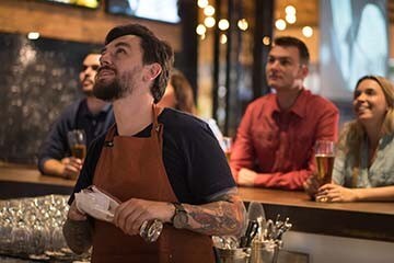 Bartender and customers watch tv in restaurant