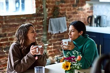  Two friends drink tea and talk at a kitchen table